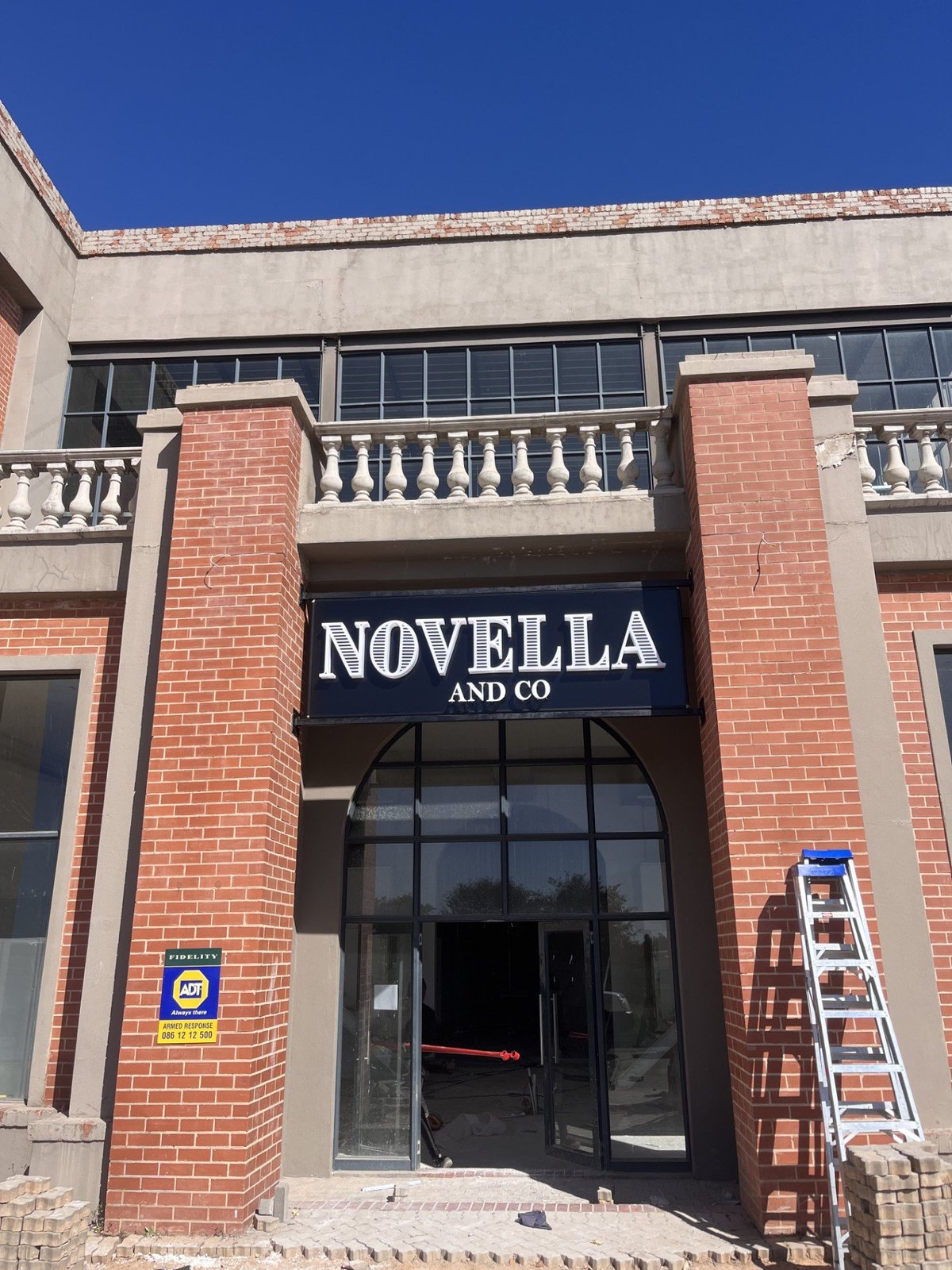 Fabricated 3D letter signage reading Novella and Co mounted on a red brick shopfront, an example of dimensional lettering installed by Imagine Graffix in Pretoria