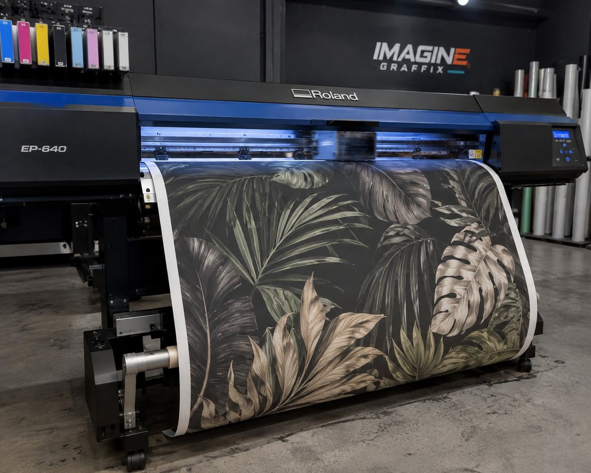 Roland EP-640 large-format printer in the Imagine Graffix N4 Gateway workshop, mid-printing a tropical leaf wallpaper mural, with ink cartridges and the Imagine Graffix logo on the wall behind